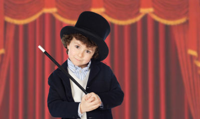 Adorable child dress of illusionist with hat and red curtains of background